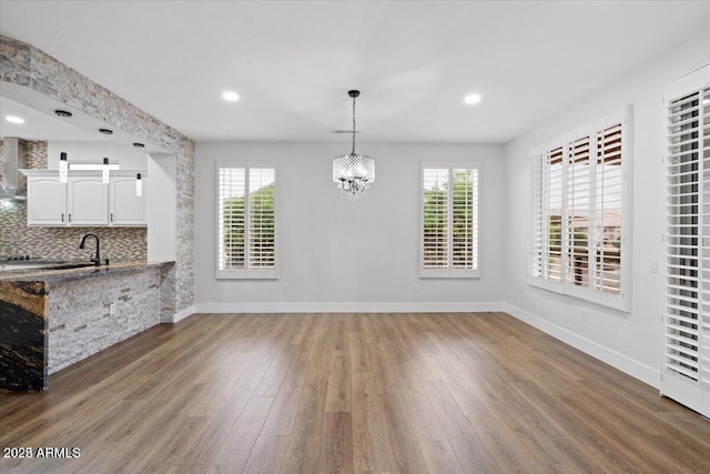 unfurnished dining area featuring a chandelier and wood-type flooring