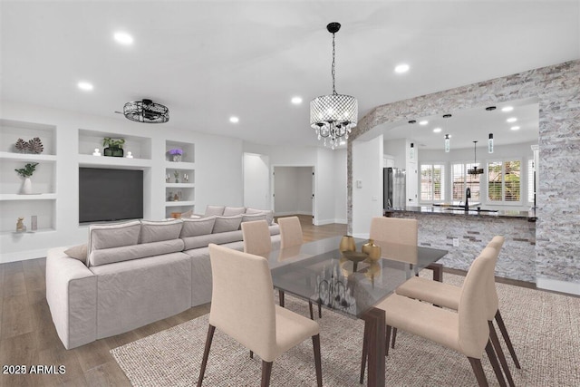 dining area featuring built in features, light hardwood / wood-style flooring, a chandelier, and sink