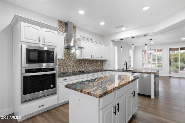 kitchen with a center island, sink, stainless steel dishwasher, wall chimney exhaust hood, and kitchen peninsula