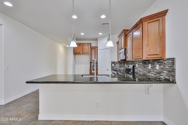 9072 W Myrtle Ave, Glendale, AZ 85305 - kitchen with appliances with stainless steel finishes, a sink, brown cabinetry, dark stone countertops, and recessed lighting