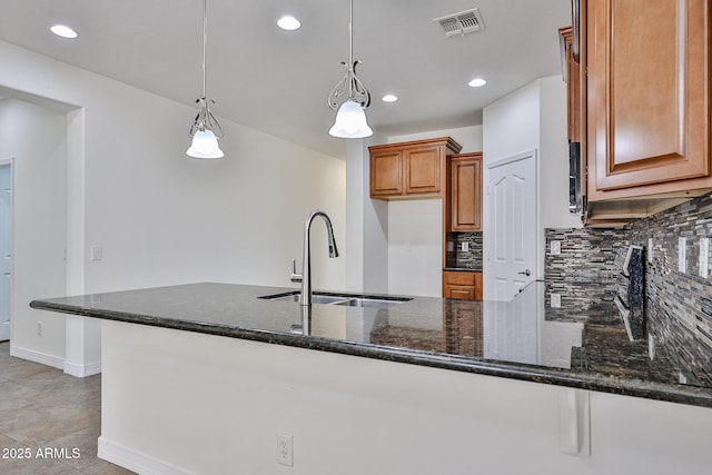 9072 W Myrtle Ave, Glendale, AZ 85305 - kitchen with a sink, dark stone countertops, a peninsula, tasteful backsplash, and brown cabinetry