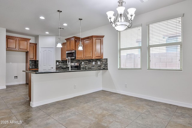 9072 W Myrtle Ave, Glendale, AZ 85305 - kitchen featuring brown cabinetry, dark countertops, stainless steel microwave, decorative backsplash, and a peninsula