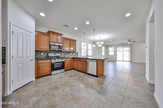 9072 W Myrtle Ave, Glendale, AZ 85305 - kitchen with appliances with stainless steel finishes, a sink, a peninsula, decorative backsplash, and brown cabinets