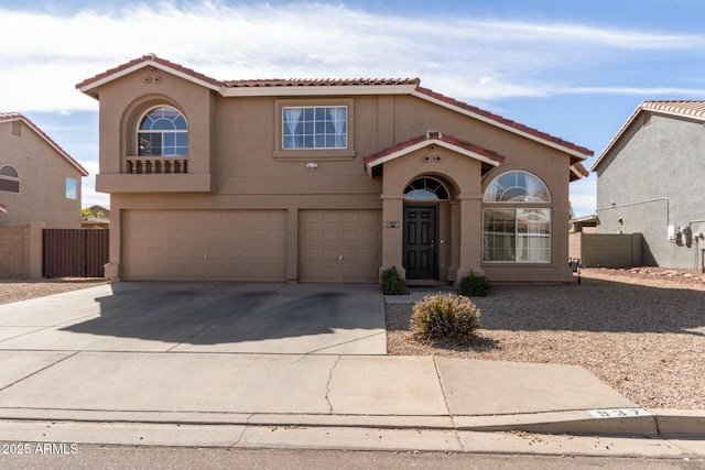 mediterranean / spanish house with concrete driveway, a tile roof, an attached garage, fence, and stucco siding