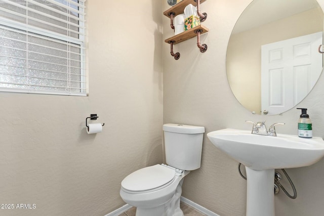 half bathroom featuring toilet, baseboards, and a sink