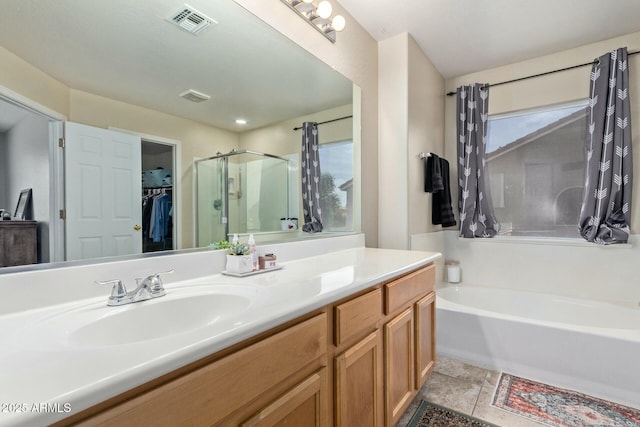 full bathroom with visible vents, a walk in closet, a bath, and vanity