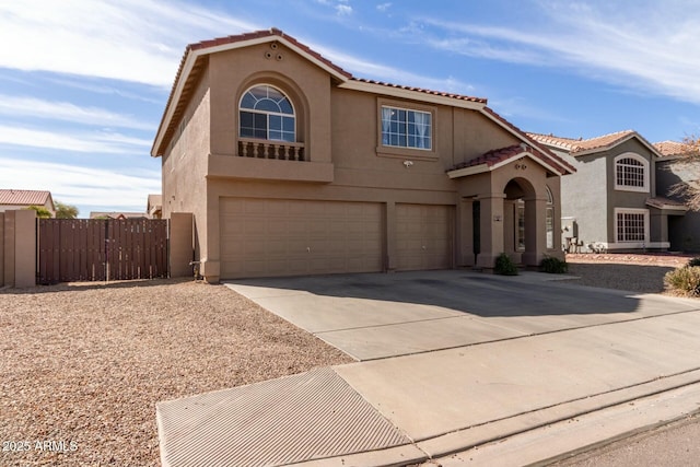 mediterranean / spanish-style house featuring a tile roof, stucco siding, an attached garage, fence, and driveway