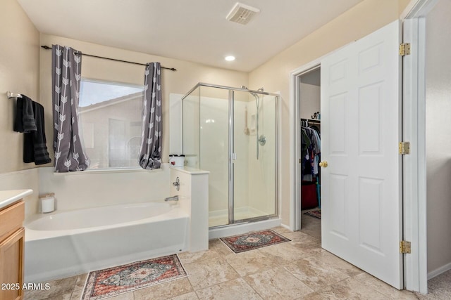 bathroom featuring a garden tub, visible vents, vanity, a spacious closet, and a stall shower