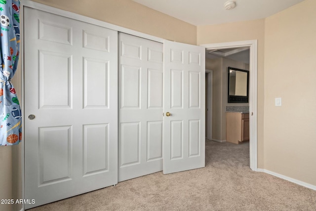 unfurnished bedroom featuring a closet, light colored carpet, and baseboards