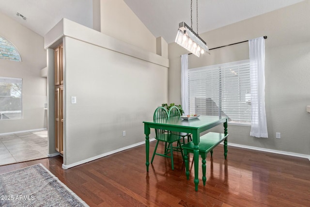 dining room with high vaulted ceiling, dark wood finished floors, visible vents, and baseboards