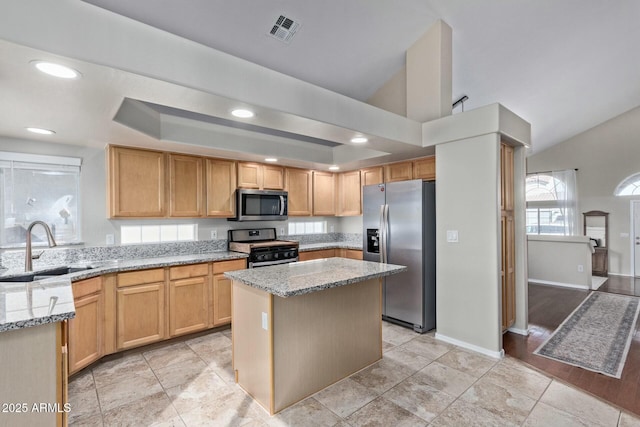 kitchen with visible vents, appliances with stainless steel finishes, light stone countertops, a tray ceiling, and a sink