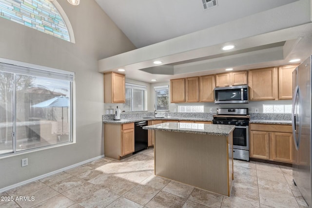 kitchen with stainless steel appliances, a tray ceiling, visible vents, and light stone countertops