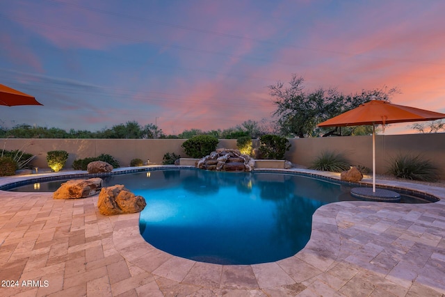 pool at dusk featuring a patio