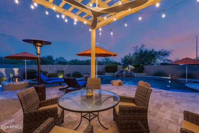 patio terrace at dusk with a fenced in pool