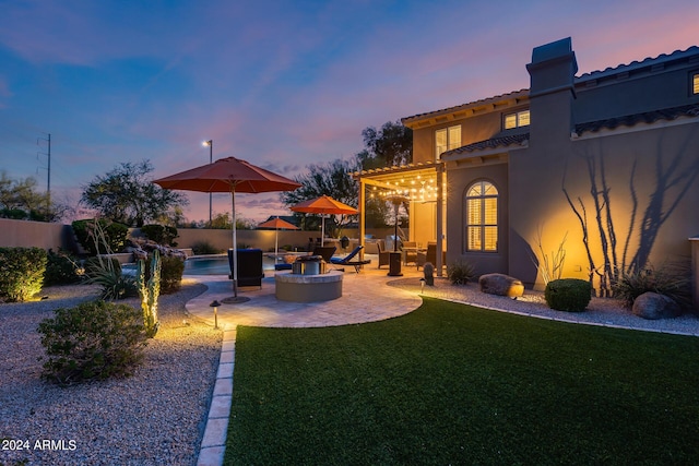 yard at dusk featuring a fenced in pool, a patio, and an outdoor fire pit