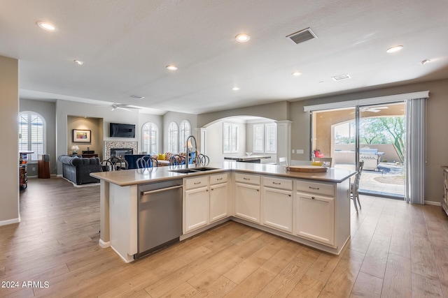 kitchen with sink, light hardwood / wood-style flooring, stainless steel dishwasher, a center island with sink, and white cabinets