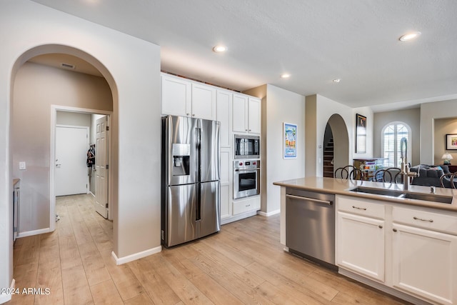 kitchen featuring white cabinets, sink, appliances with stainless steel finishes, and light hardwood / wood-style flooring