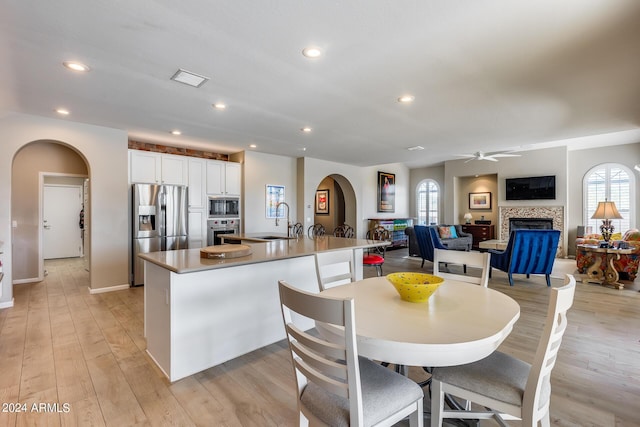 kitchen featuring a tile fireplace, white cabinetry, a large island, sink, and stainless steel appliances