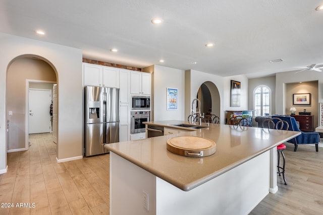 kitchen featuring white cabinetry, a large island, sink, stainless steel appliances, and a breakfast bar area