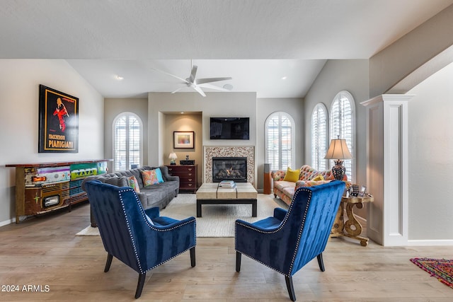 living room with ceiling fan, light wood-type flooring, a fireplace, and decorative columns