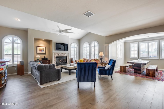 living room with a tiled fireplace, ceiling fan, hardwood / wood-style floors, and ornate columns