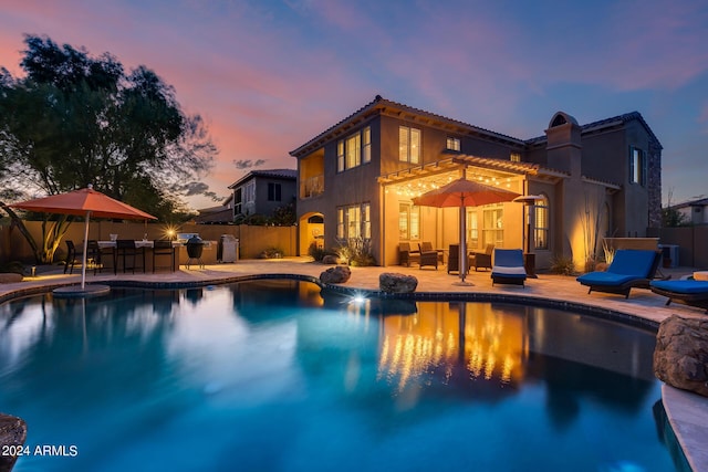 pool at dusk featuring a patio