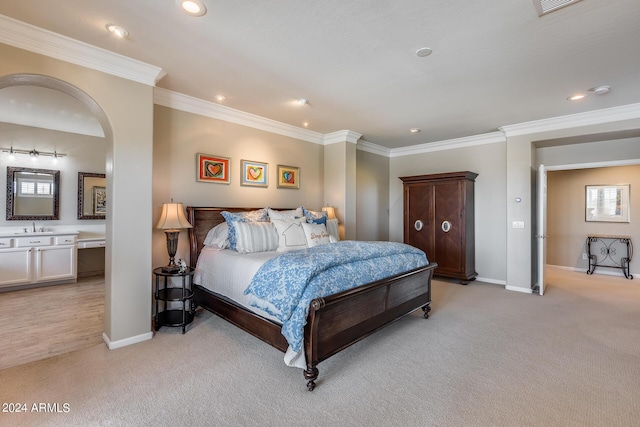 carpeted bedroom with ornamental molding and ensuite bath