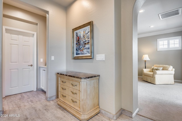 hallway featuring crown molding and light carpet