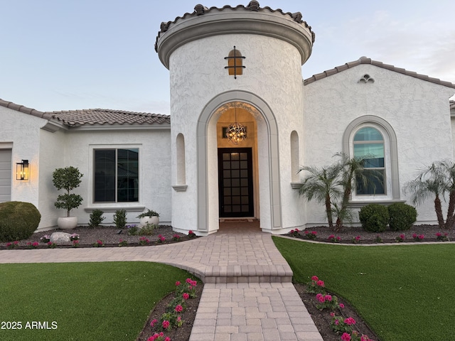 doorway to property with a yard, a tile roof, and stucco siding