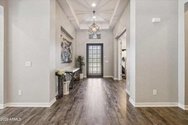 entryway featuring a tray ceiling, dark wood-style flooring, and baseboards