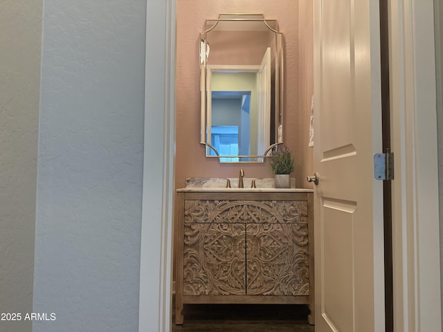 bathroom with a textured wall and vanity