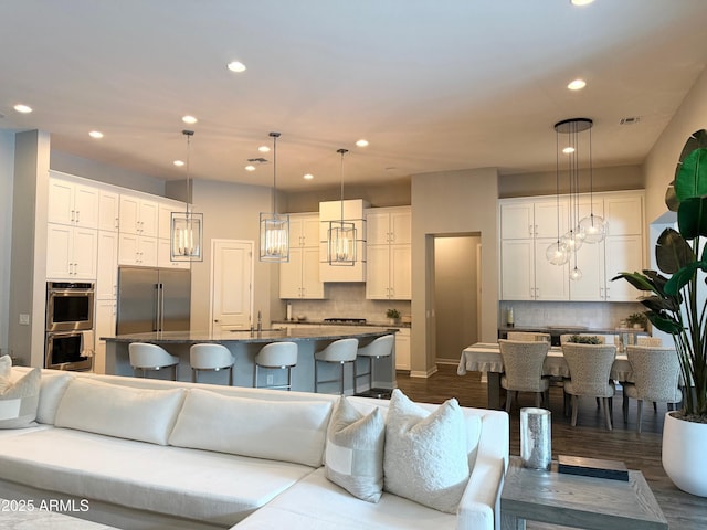 living room featuring dark wood-type flooring, visible vents, and recessed lighting