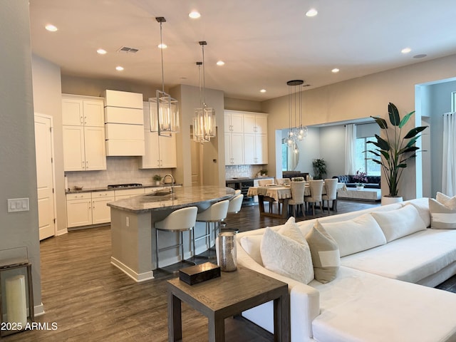 kitchen with a notable chandelier, stainless steel gas cooktop, a sink, visible vents, and open floor plan