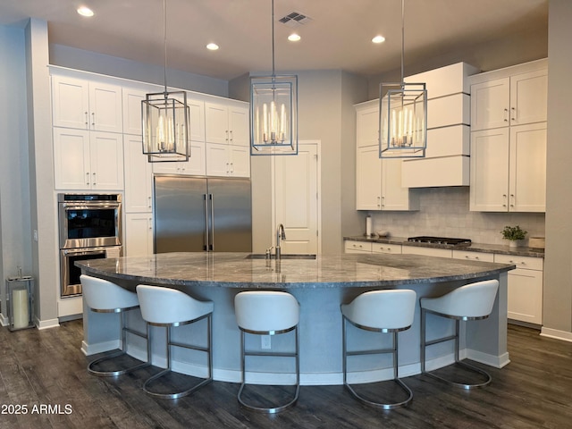 kitchen featuring stainless steel appliances, visible vents, decorative backsplash, white cabinets, and a sink