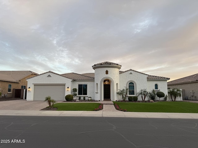 mediterranean / spanish-style home featuring driveway, a front lawn, an attached garage, and a tile roof