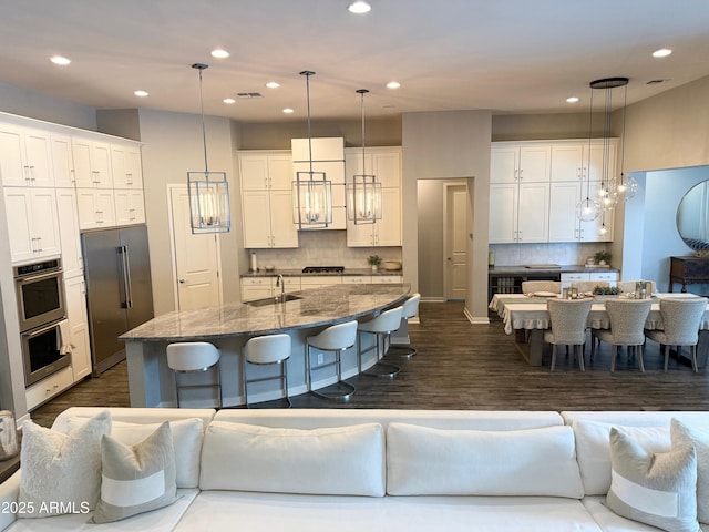 kitchen with appliances with stainless steel finishes, a sink, white cabinetry, and a kitchen breakfast bar