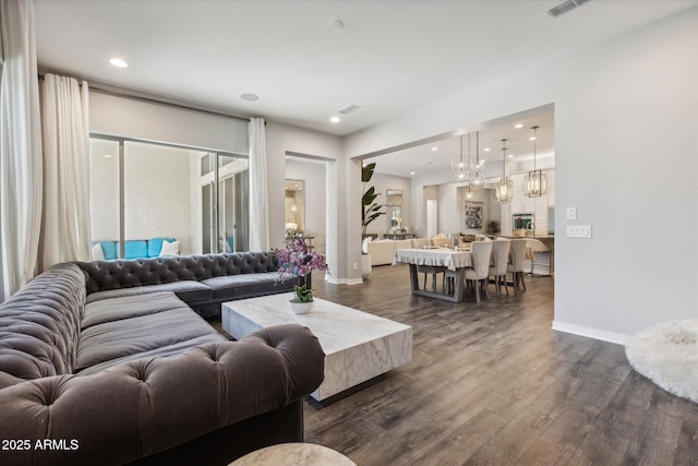 living room with baseboards, recessed lighting, dark wood finished floors, and a notable chandelier