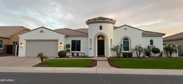 mediterranean / spanish home featuring driveway, a tile roof, a front lawn, and stucco siding