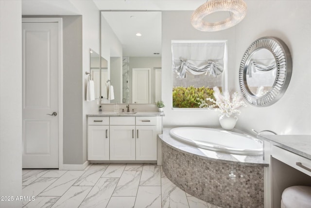 bathroom featuring marble finish floor, a garden tub, and vanity