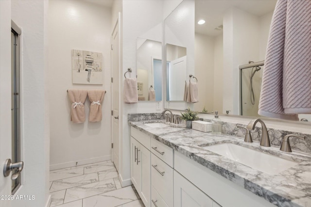 bathroom with marble finish floor, double vanity, a sink, and baseboards