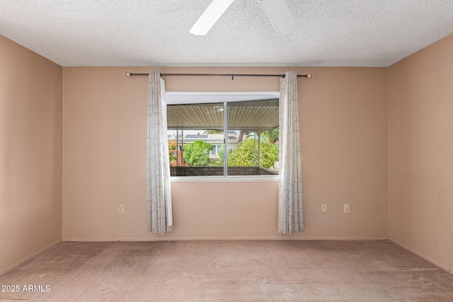 carpeted spare room featuring baseboards, a textured ceiling, and a ceiling fan