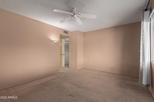 carpeted empty room featuring a ceiling fan, visible vents, and a textured ceiling