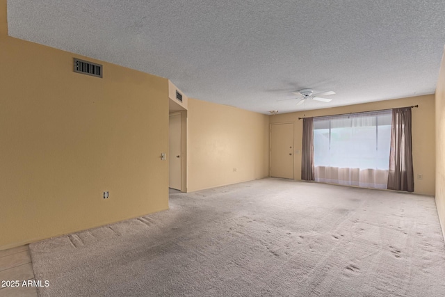 carpeted empty room with visible vents, a textured ceiling, and a ceiling fan