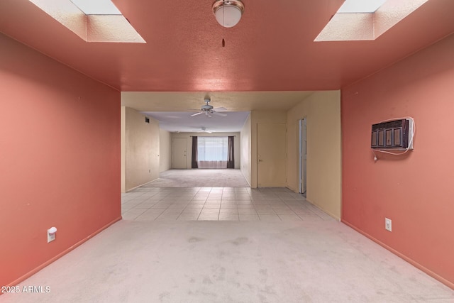 hall with tile patterned flooring, a skylight, carpet floors, and a textured ceiling