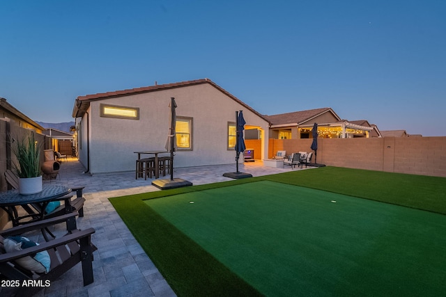 back house at dusk with a patio