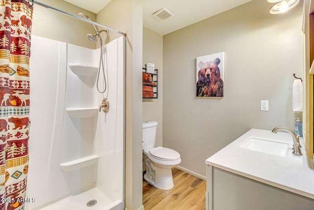 bathroom with toilet, wood finished floors, vanity, visible vents, and a stall shower