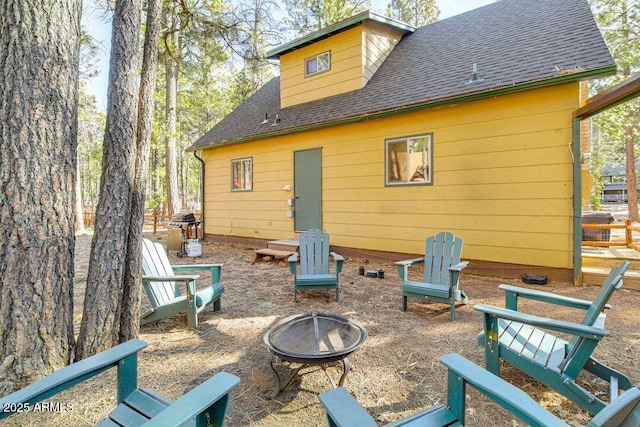 rear view of house with roof with shingles and a fire pit