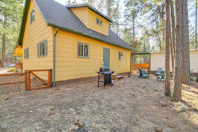 back of house featuring roof with shingles and fence