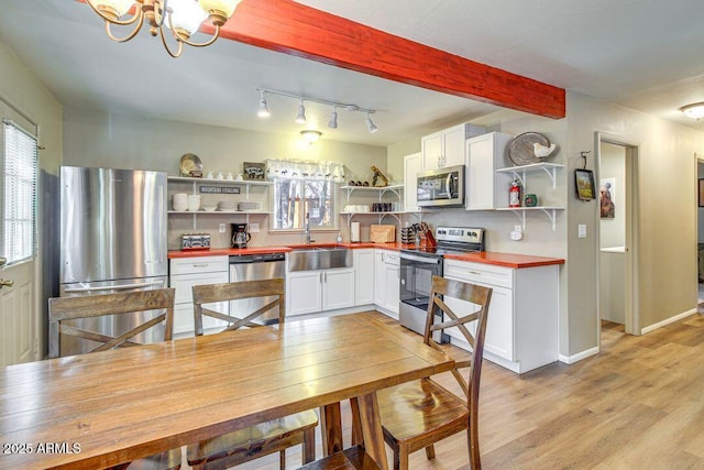 kitchen featuring light wood-style floors, appliances with stainless steel finishes, open shelves, and a sink