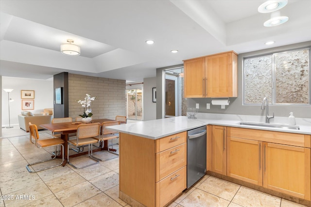 kitchen featuring open floor plan, a peninsula, a tray ceiling, light countertops, and a sink